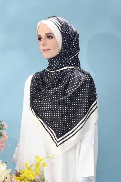 Black and white polka dot hijab with stripe accents on model against a blue backdrop