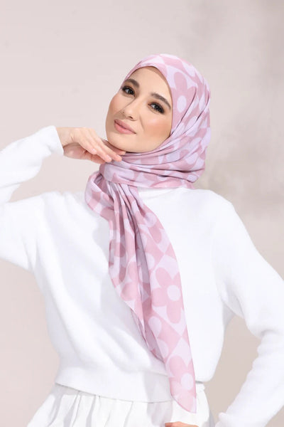 A model wearing a soft pink hijab adorned with a subtle floral pattern, radiating elegance and grace