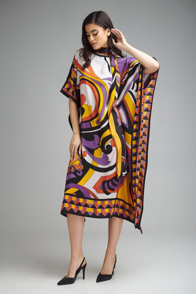A model stands showcasing a colorful kaftan with a geometric and swirl pattern in purple, yellow, and orange tones