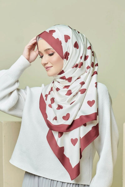 White hijab with red heart patterns and border, fashionably styled, ideal for modest wear