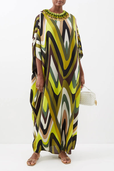 Full length kaftan dress with a wavy pattern in shades of olive green, mustard, and brown, featuring a ruffled green neckline and loose, flowy sleeves.