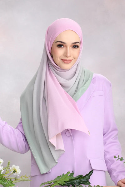 Woman in a pastel sage green scarf paired with a light pink under-scarf embodying modern modest fashion.