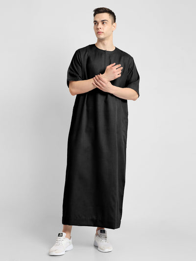 Man wearing a black, ankle-length thobe with a relaxed fit, embodying a fusion of traditional charm and modern simplicity