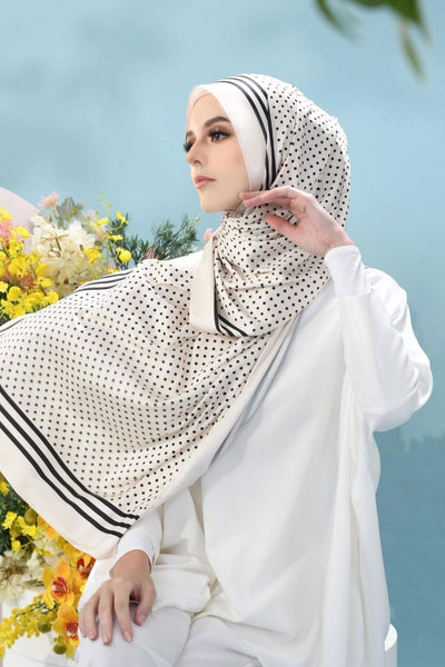 Woman wearing a stylish white and black polka-dot hijab with elegant draping, ideal for modern modest fashion